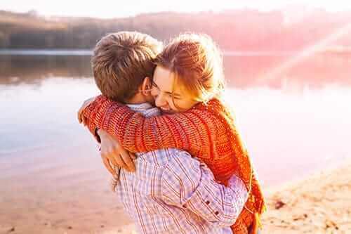 two people hug by a lake because they are happy about their addiction treatment programs