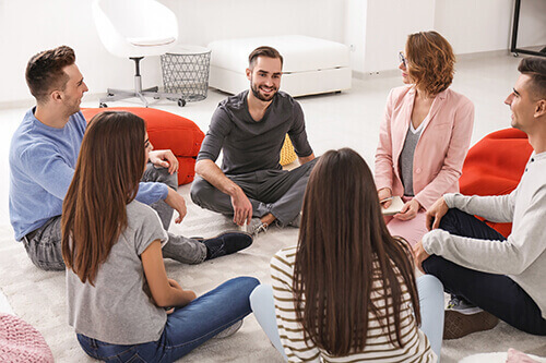 Group of individuals sitting on the floor discuss humana drug rehab coverage