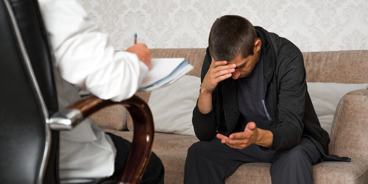 young man is sitting on couch and talking to the psychologist